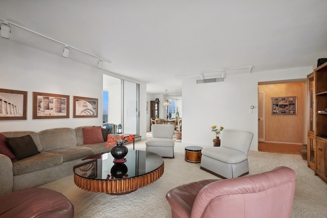 living area featuring a chandelier, rail lighting, light carpet, and visible vents