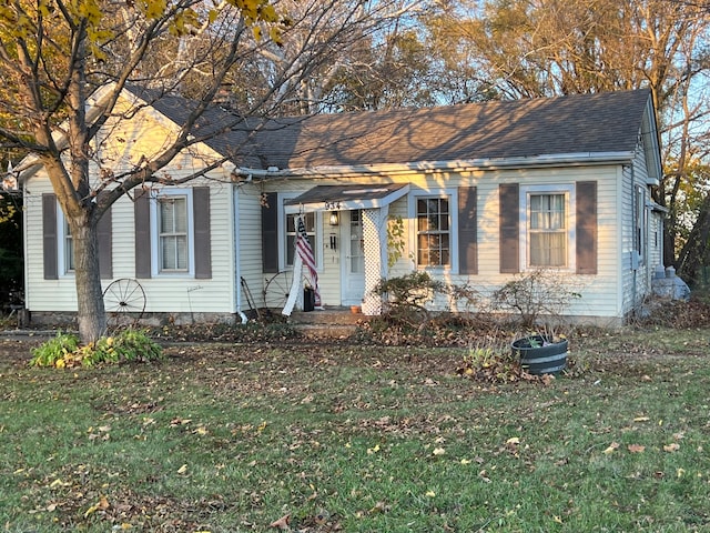 view of front facade with a shingled roof and a front yard