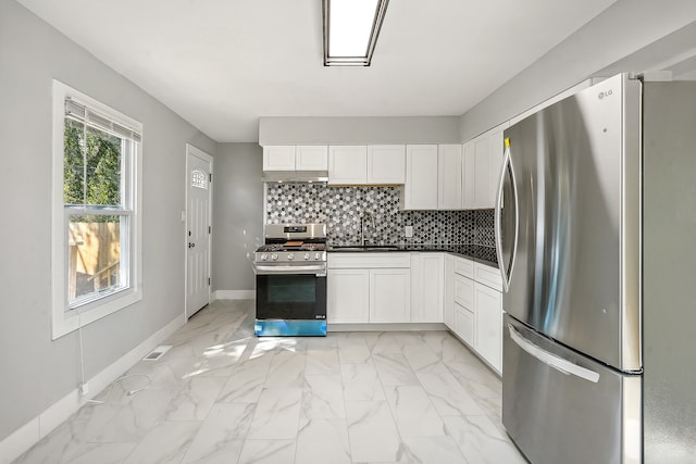 kitchen featuring stainless steel appliances, decorative backsplash, white cabinetry, and sink