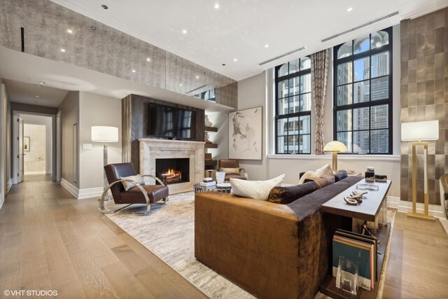 living room featuring a high end fireplace and light wood-type flooring