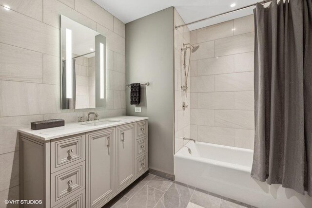 bathroom with tile walls, shower / bath combination with curtain, tile patterned floors, and vanity