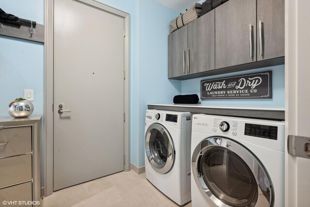 clothes washing area featuring washing machine and dryer, cabinets, and light tile patterned floors