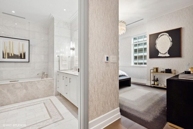 bathroom featuring tile patterned flooring, tiled bath, crown molding, and vanity