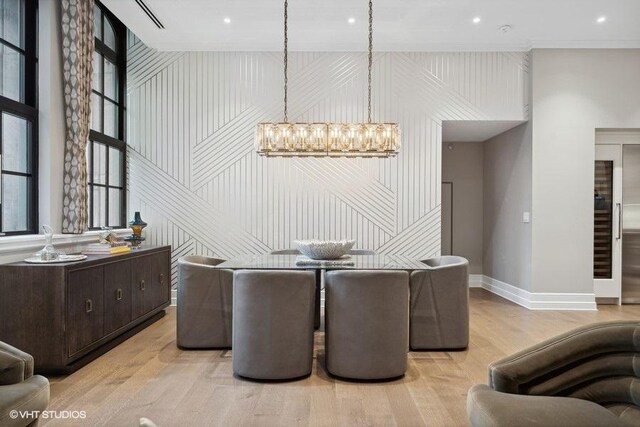 dining space featuring a notable chandelier, crown molding, and light wood-type flooring