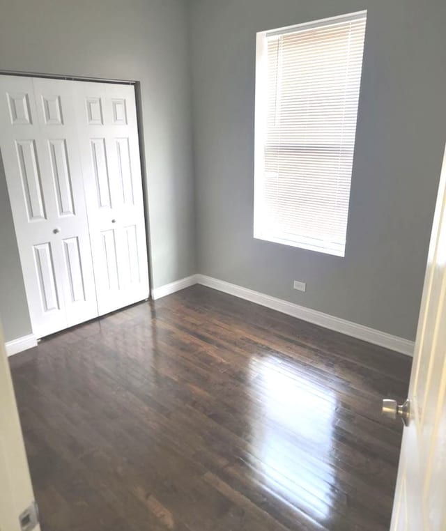 unfurnished bedroom featuring dark hardwood / wood-style flooring and a closet