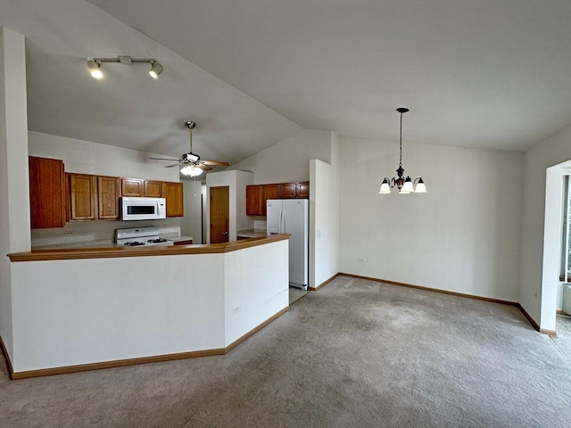 kitchen featuring ceiling fan with notable chandelier, white appliances, light colored carpet, vaulted ceiling, and hanging light fixtures