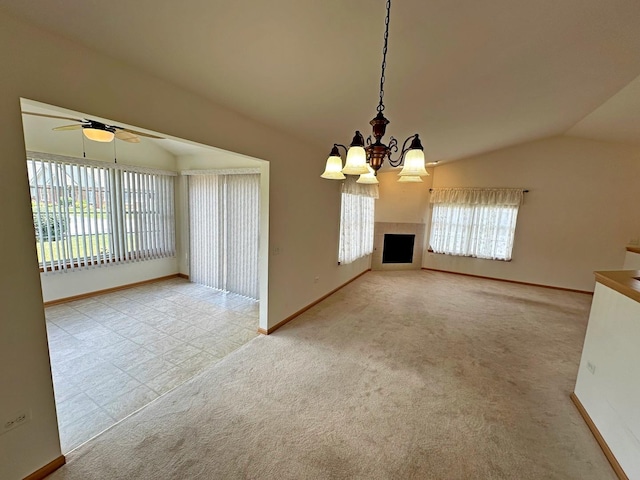 unfurnished dining area with ceiling fan with notable chandelier, a healthy amount of sunlight, light colored carpet, and vaulted ceiling