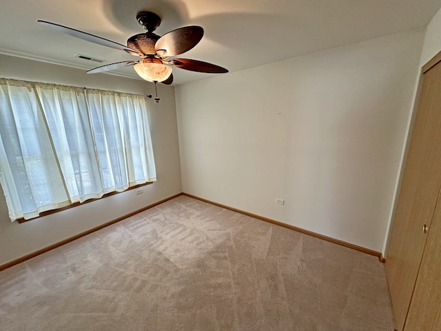 spare room with ceiling fan and light colored carpet