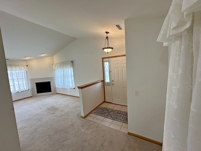 entrance foyer with light tile patterned floors, lofted ceiling, and a tiled fireplace