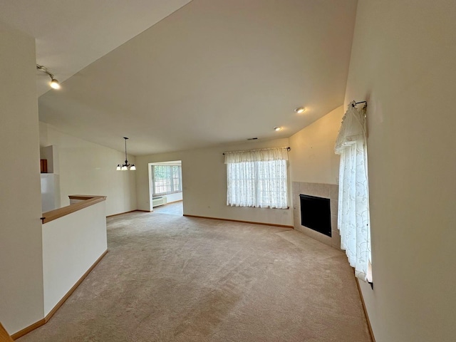 unfurnished living room with light carpet, vaulted ceiling, baseboard heating, a notable chandelier, and a tiled fireplace