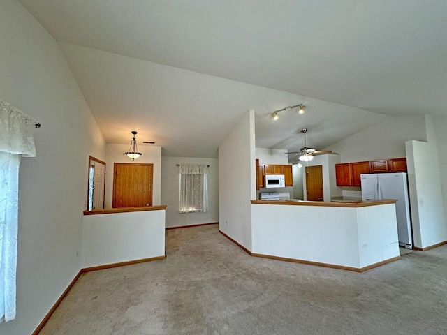 kitchen featuring white appliances, vaulted ceiling, ceiling fan, light colored carpet, and kitchen peninsula