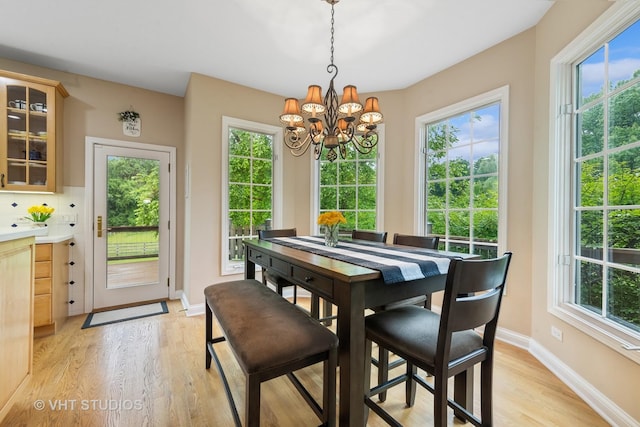 dining area featuring a notable chandelier, plenty of natural light, and light wood-type flooring