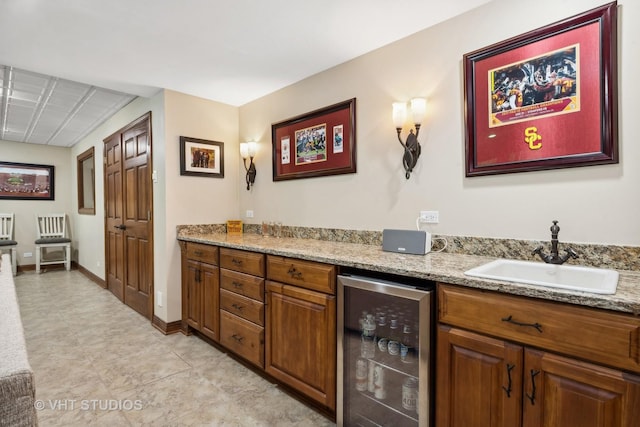 kitchen featuring light stone counters, beverage cooler, and sink