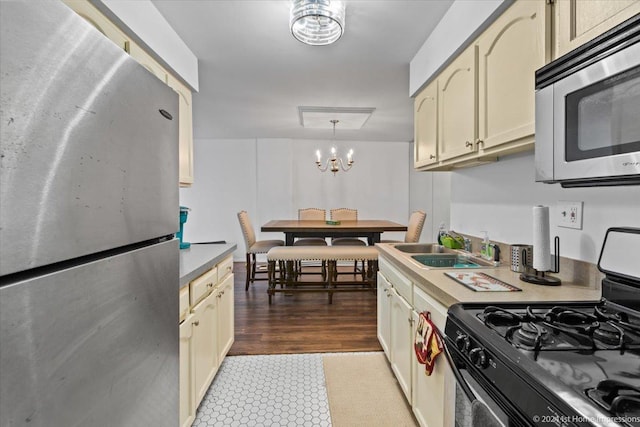 kitchen with sink, hanging light fixtures, stainless steel appliances, a chandelier, and cream cabinetry