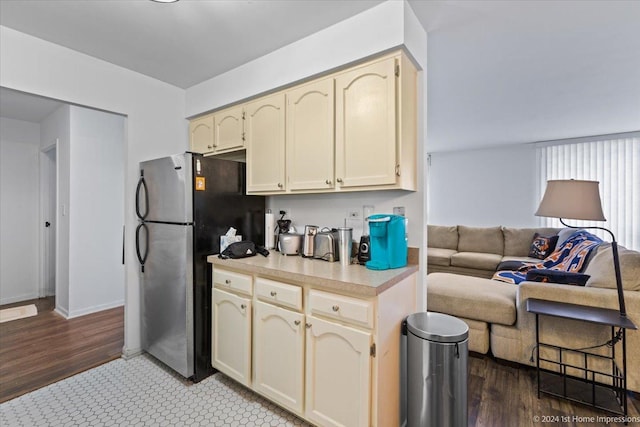 kitchen with stainless steel fridge, cream cabinets, and dark hardwood / wood-style floors