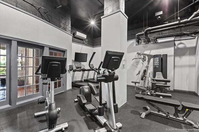 workout area featuring a high ceiling and a wall unit AC