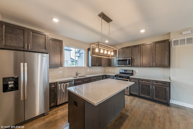 kitchen with dark hardwood / wood-style floors, stainless steel appliances, hanging light fixtures, and a center island