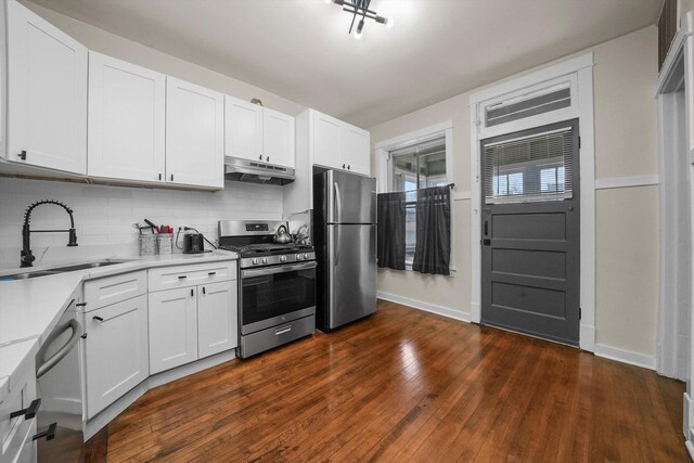 kitchen with dark wood-type flooring, appliances with stainless steel finishes, white cabinets, sink, and tasteful backsplash