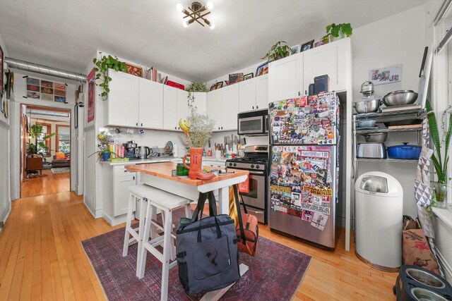 kitchen with light hardwood / wood-style flooring, stainless steel appliances, and white cabinetry