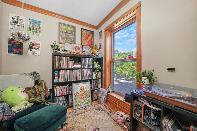 living area featuring crown molding and light hardwood / wood-style floors