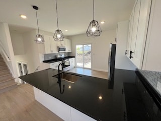 kitchen featuring sink, range, white cabinets, and light wood-type flooring