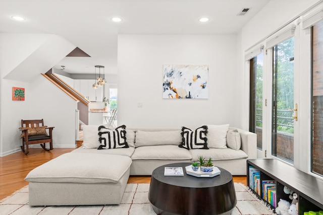 living room with light hardwood / wood-style floors and an inviting chandelier