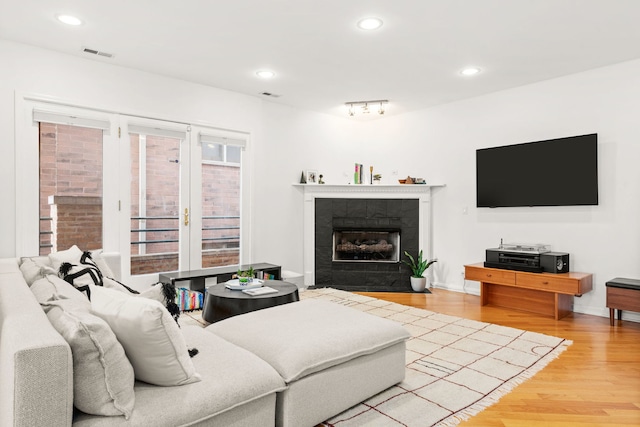 living room with a fireplace and light wood-type flooring