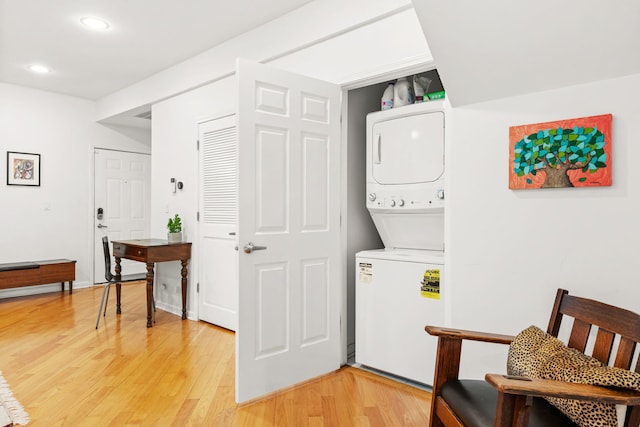 clothes washing area featuring light hardwood / wood-style floors and stacked washer / drying machine