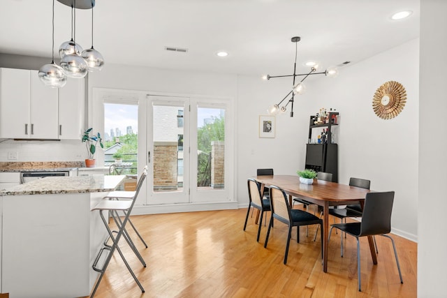 dining area with a notable chandelier and light hardwood / wood-style flooring