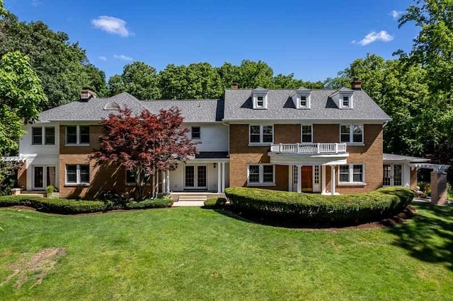 rear view of property with a balcony and a yard