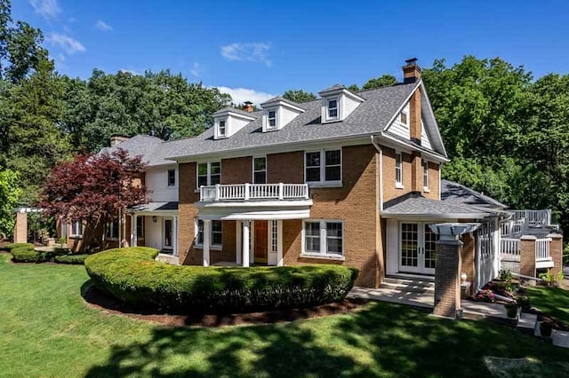 rear view of house featuring a balcony, french doors, and a yard