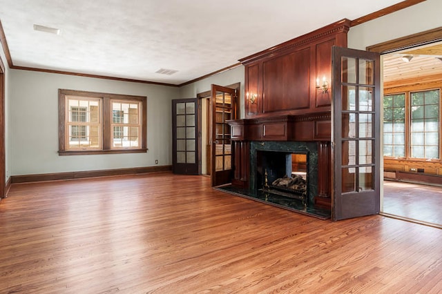 unfurnished living room with ornamental molding, hardwood / wood-style floors, a high end fireplace, and plenty of natural light