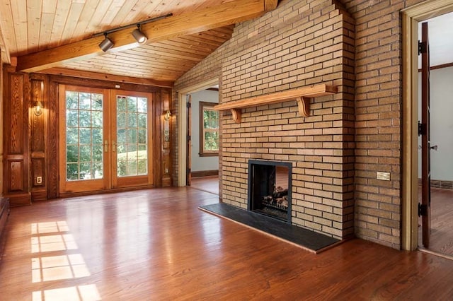 unfurnished living room with wood ceiling, track lighting, a brick fireplace, hardwood / wood-style flooring, and lofted ceiling with beams