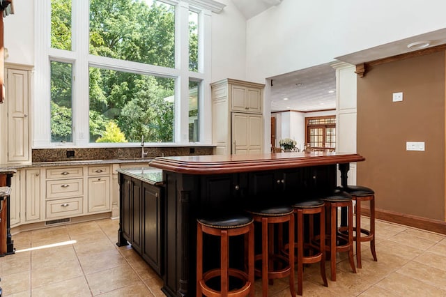 interior space with light tile patterned flooring, a healthy amount of sunlight, a towering ceiling, and light stone counters