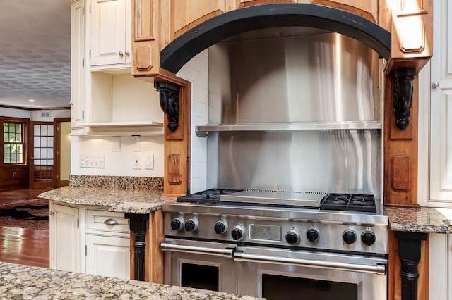 kitchen featuring wood-type flooring, double oven range, and light stone counters