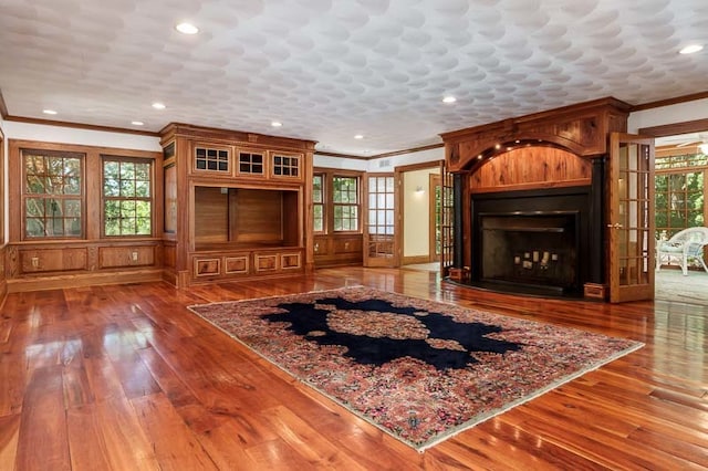 unfurnished living room with ornamental molding, wood-type flooring, and plenty of natural light