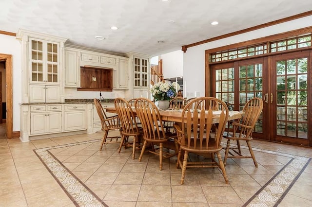 tiled dining room featuring crown molding and french doors