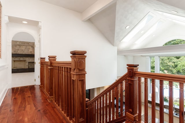 hallway with a skylight, beamed ceiling, wood-type flooring, and high vaulted ceiling