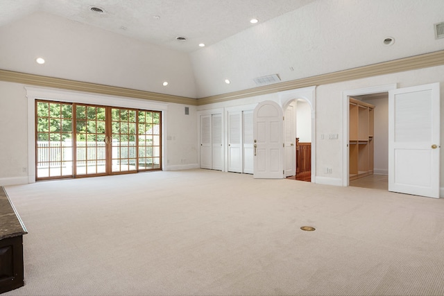 unfurnished living room with carpet floors, crown molding, and high vaulted ceiling