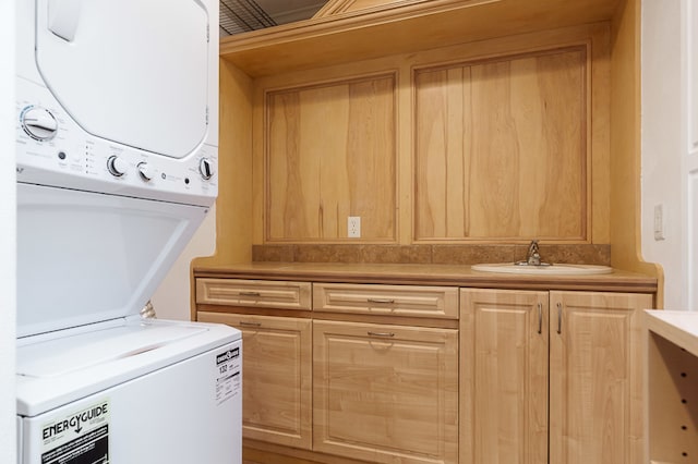 clothes washing area with cabinets, sink, and stacked washer / dryer