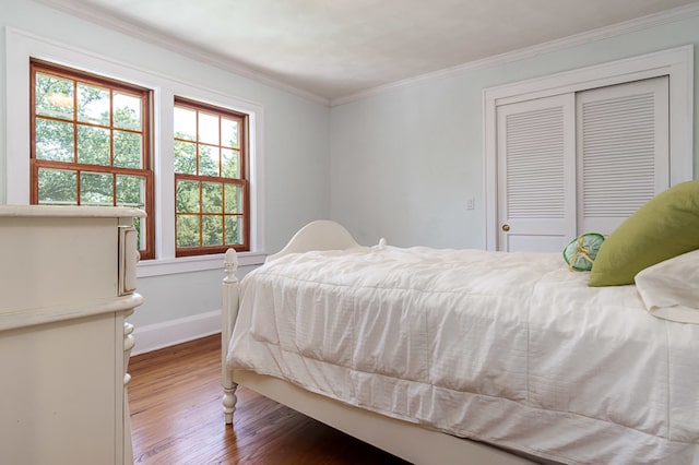 bedroom with hardwood / wood-style flooring, crown molding, and a closet