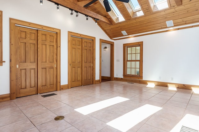 tiled spare room with ceiling fan, rail lighting, high vaulted ceiling, a skylight, and wood ceiling