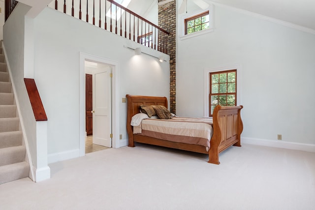 carpeted bedroom with brick wall, ornamental molding, and a towering ceiling