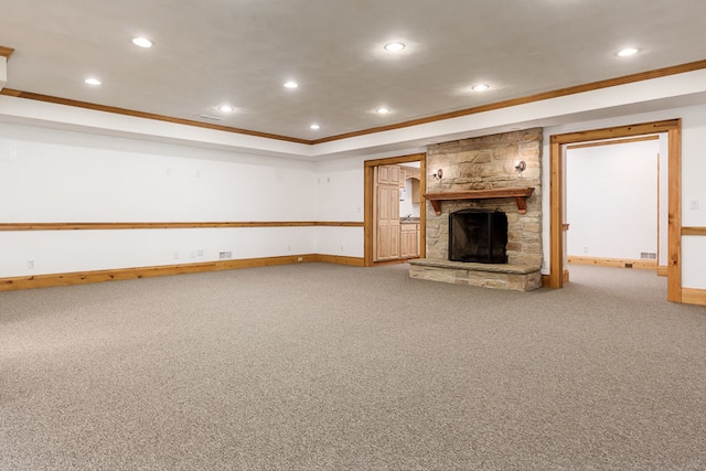 unfurnished living room featuring crown molding, a stone fireplace, and carpet