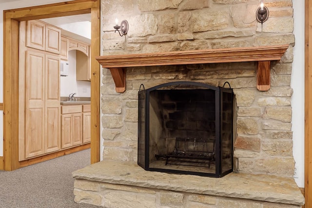 details featuring sink, carpet floors, and a stone fireplace