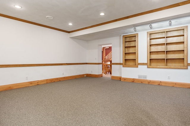 basement with built in shelves, crown molding, rail lighting, and carpet floors