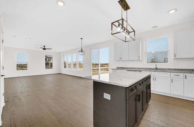 kitchen featuring light hardwood / wood-style floors, white cabinetry, pendant lighting, and light stone counters