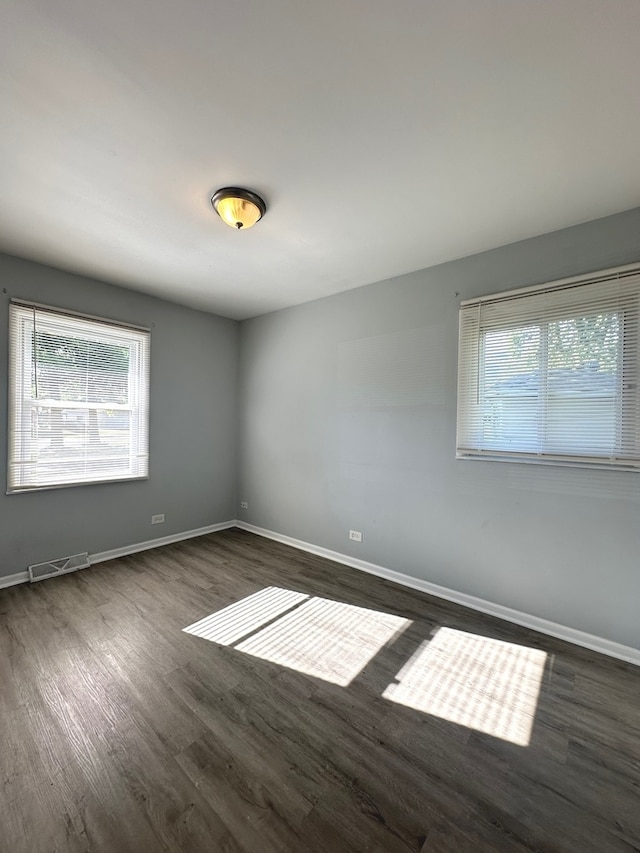 unfurnished room featuring a wealth of natural light and dark hardwood / wood-style floors