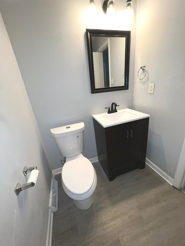 bathroom with vanity, toilet, and hardwood / wood-style floors