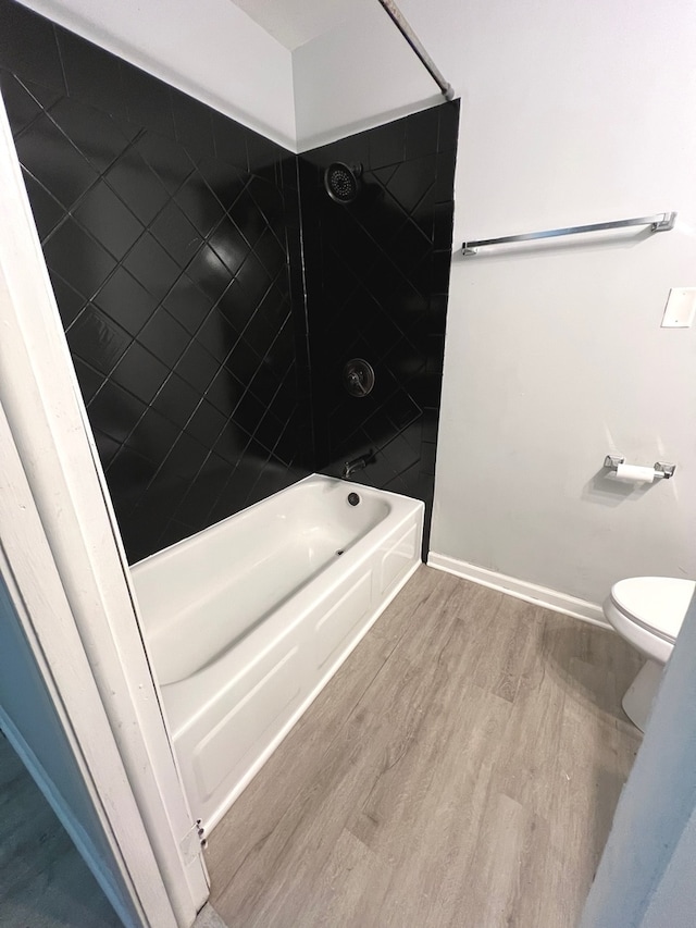 bathroom with wood-type flooring, toilet, and tiled shower / bath